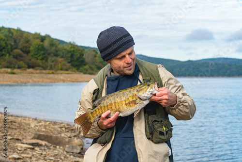 man with big bass trophy fish fall season catch, smallmouth bass copy space background image, happy fun leisure activity