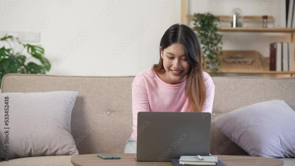 Pretty Asian woman using laptop computer on sofa. Pretty Asian woman using laptop computer on sofa.