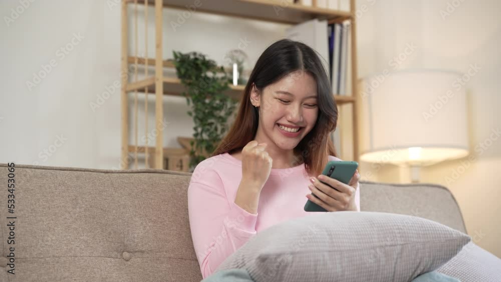 Young asian woman playing mobile games on sofa. Young asian woman playing mobile games on sofa.