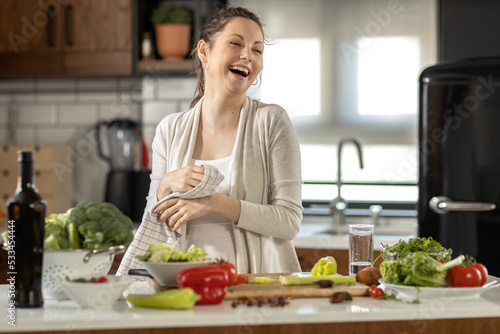 Happy pregnant woman prepare healthy food in the kitchen with smile on her face