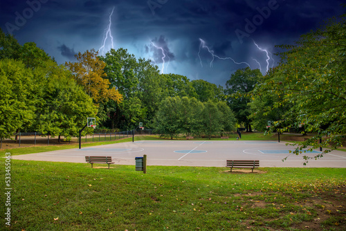 a gorgeous autumn landscape on the basketball court at Frazier Park surrounded by lush green trees and grass and autumn colored trees and powerful storm clouds and lightning in in Charlotte photo