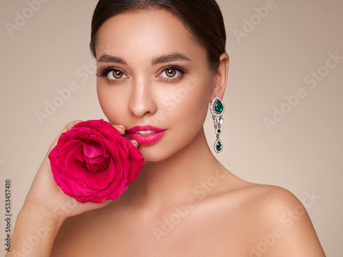 A beautiful young woman with shiny brunette hair. Girl with a rose flower. Model with healthy skin. Cosmetology  beauty and spa