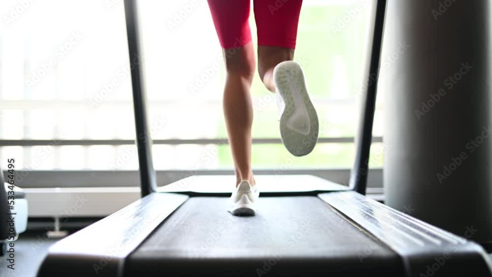 Detail of a woman's legs running on a treadmill in a gym Detail of a woman's legs running on a treadmill in a gym