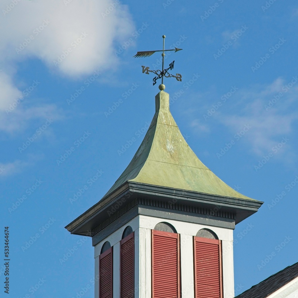 Cupola with copper cap wind vane against blue skies Cupola with copper cap wind vane against blue skies