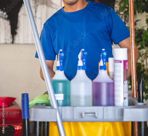 Φωτογραφία Young latino janitorial worker in blue uniform and trolley with tools and clean