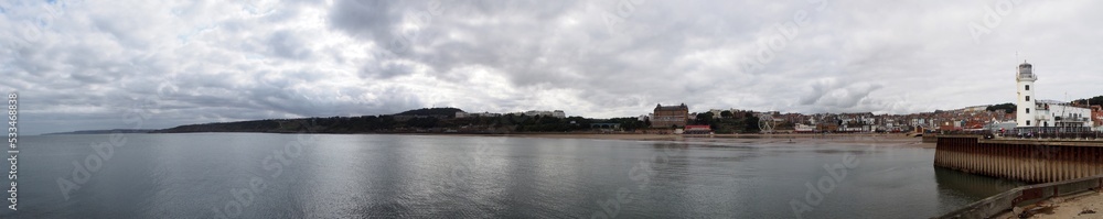 Long panoramic view of the lighthouse and town of Scarborough from the harbour wall looking out to sea