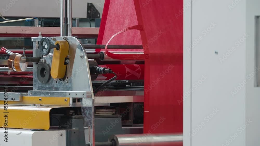 Production Machine Processing Red Eco Fabric Material With Roller Mechanisms. Automated Production Of Spunbond Sustainable Fabric By Automated Machine. Machine Producing Fabric With Handles For Bags Production Machine Processing Red Eco Fabric Material With Roller Mechanisms. Automated Production Of Spunbond Sustainable Fabric By Automated Machine. Machine Producing Fabric With Handles For Bags