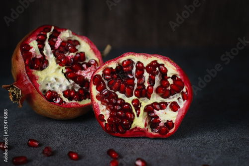 close up of a cut pomegranate on grey table and wooden dark background