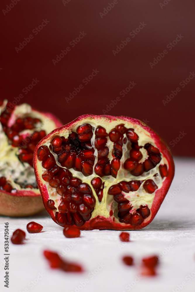close up of a cut pomegranate on white table, red background with copy space close up of a cut pomegranate on white table, red background with copy space