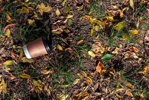 A cup of coffee thrown on the ground. An empty paper coffee cup lies on the ground