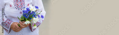 An old Ukrainian woman in an embroidered shirt with a bouquet of flowers. Selective focus. photo