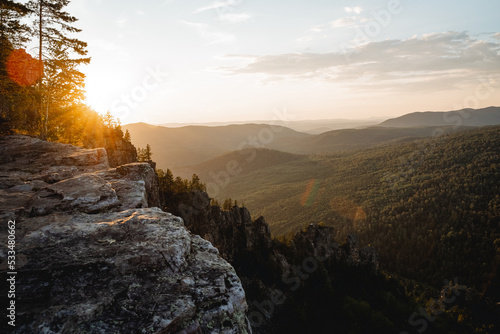 The evening sunset sun shines behind the mountain, the glare of the sun of beautiful color, the mountain landscape of the ridge of the southern Urals russia, the panorama at the top of the cliff. photo