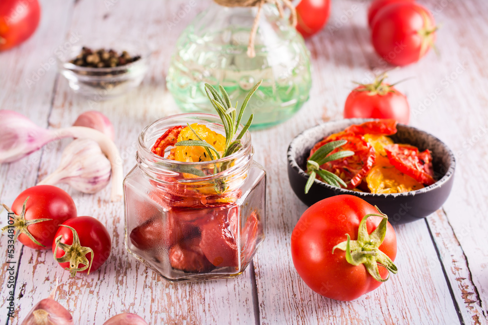 Homemade sun-dried tomatoes with spices, garlic and herbs in a jar and fresh vegetables on the table. Homemade sun-dried tomatoes with spices, garlic and herbs in a jar and fresh vegetables on the table.