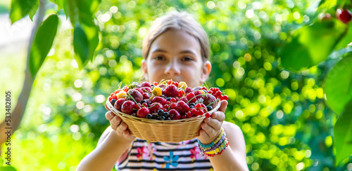 The child eats berries in the garden. Selective focus.