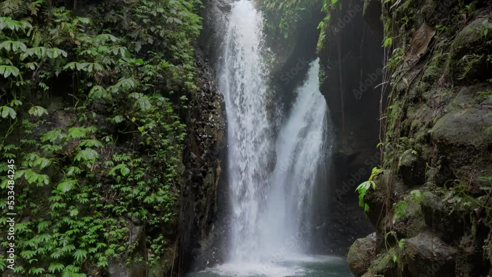 Fabulous wild nature in tropical rainforest. Green vegetation on rocks against water streams falling down on river cascade in the jungle. Splashes of roaring waterfall for natural background design. Fabulous wild nature in tropical rainforest. Green vegetation on rocks against water streams falling down on river cascade in the jungle. Splashes of roaring waterfall for natural background design.