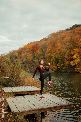 A young beautiful woman is doing sports in the autumn forest