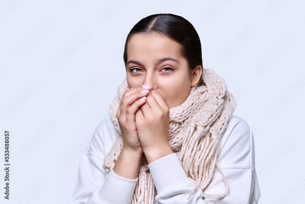 Winter portrait of young female in sweater scarf, on light studio background Winter portrait of young female in sweater scarf, on light studio background