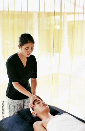 Woman receiving a facial at the outdoor relaxation pavilion at a resort spa. Bali, Indonesia photo