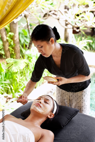 Woman receiving a facial at the outdoor relaxation pavilion at a resort spa. Bali, Indonesia photo