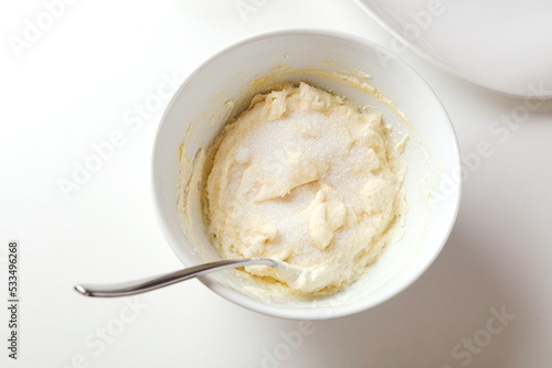 Photographic Recipe of Ukrainian Cottage Cheese Pancakes, Also Known as Syrnyky. Step 3: Add  Vanilla, One Spoon of Sugar, One Spoon of Flour. Stir.