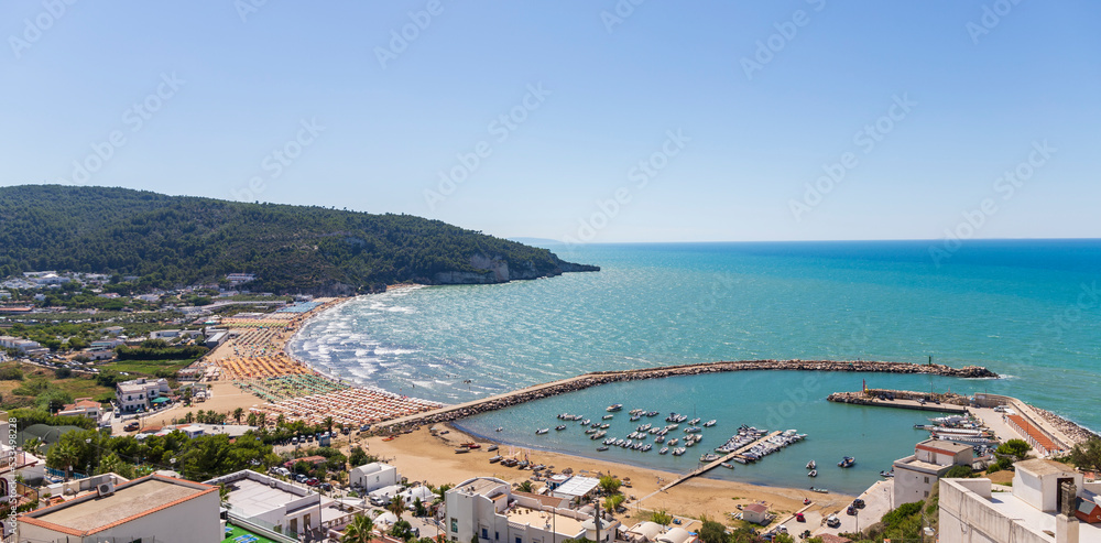 Aerial view on the beaches, sea, pier and boats of Peschici, Gargano, Puglia, Italy.