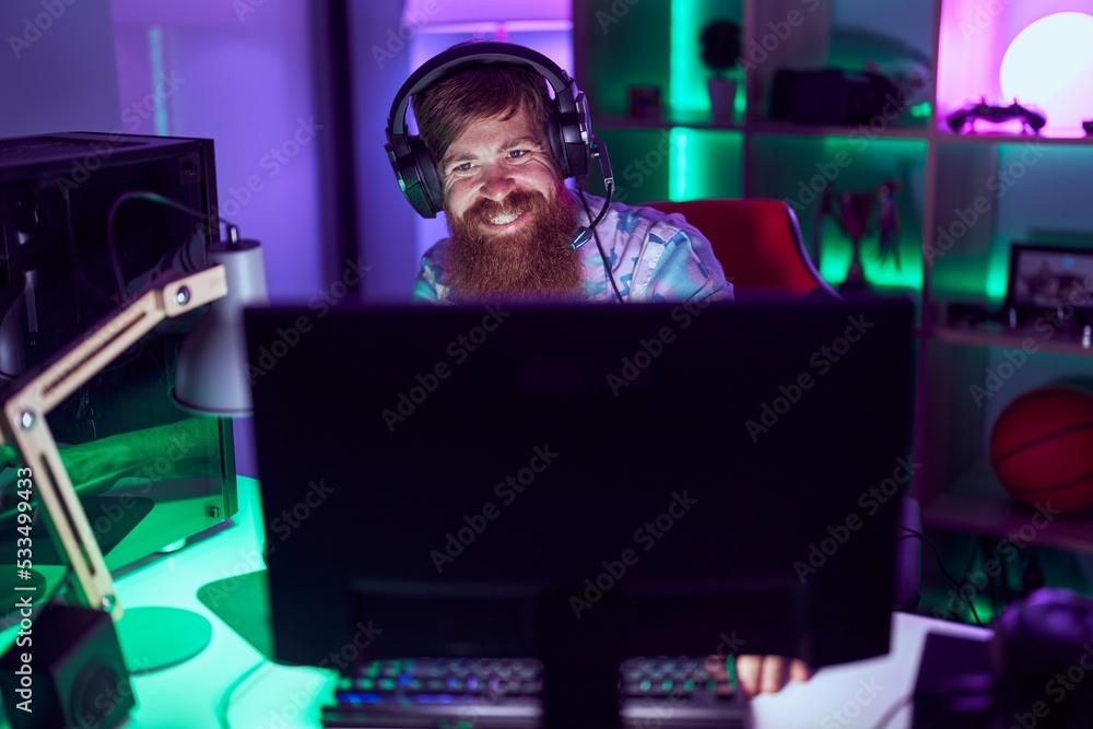 Young redhead man streamer playing video game using computer at gaming room Young redhead man streamer playing video game using computer at gaming room