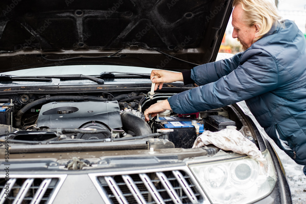 The man inserted an iron dipstick into the engine crankcase to check the oil level in the car engine The man inserted an iron dipstick into the engine crankcase to check the oil level in the car engine