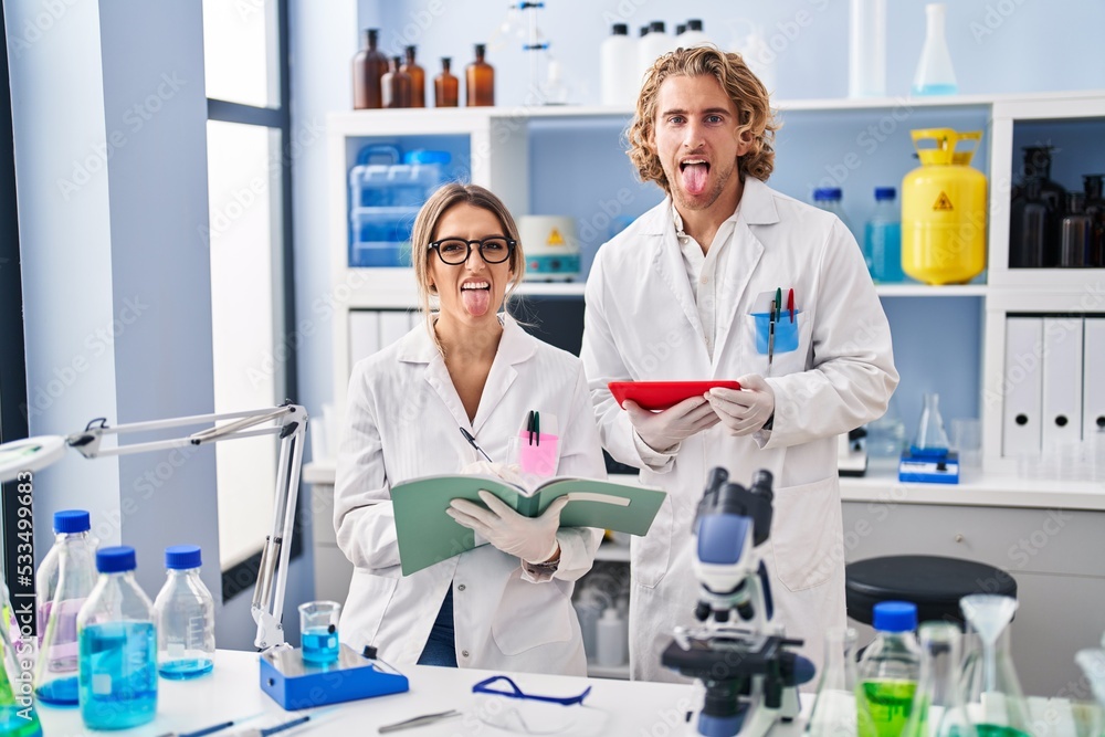 Two people working at scientist laboratory sticking tongue out happy with funny expression. Two people working at scientist laboratory sticking tongue out happy with funny expression.