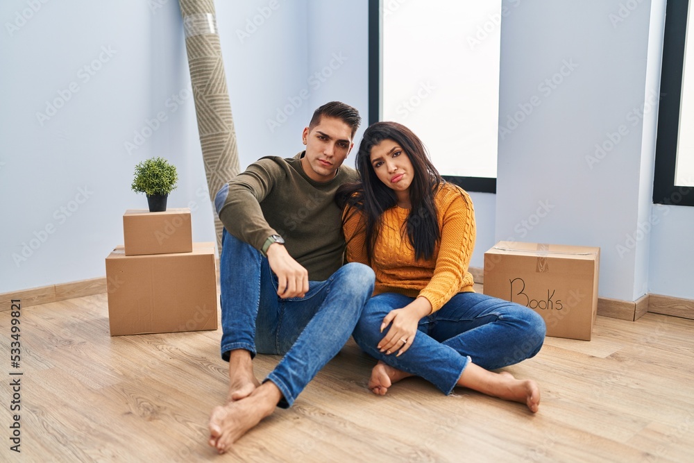 Young couple sitting on the floor at new home depressed and worry for distress, crying angry and afraid. sad expression. Young couple sitting on the floor at new home depressed and worry for distress, crying angry and afraid. sad expression.