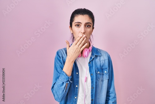 Young beautiful woman standing over pink background bored yawning tired covering mouth with hand. restless and sleepiness.
