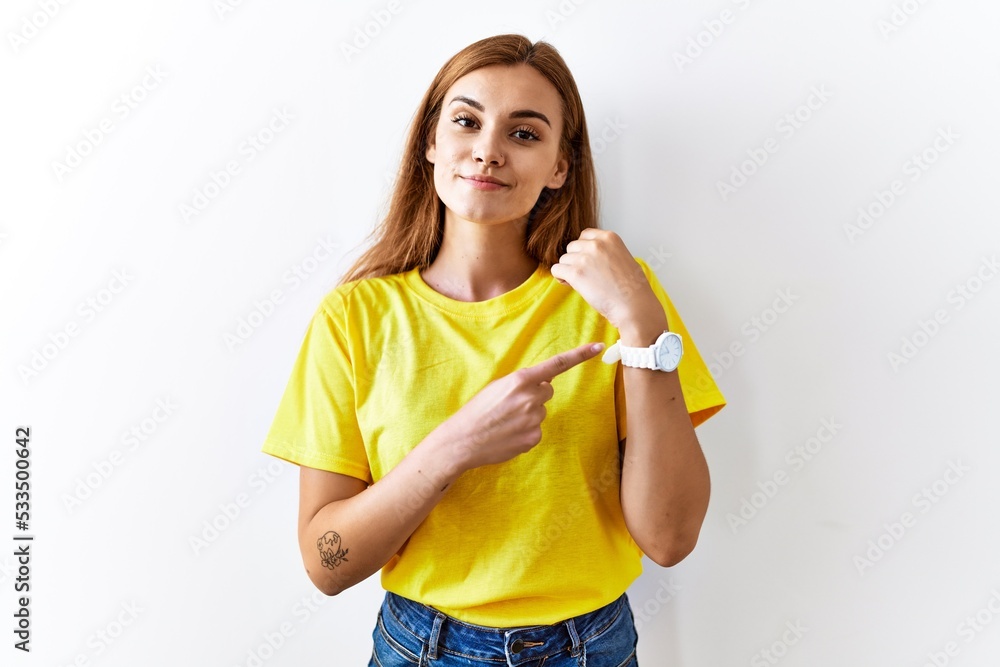 Young brunette woman standing over isolated background in hurry pointing to watch time, impatience, looking at the camera with relaxed expression Young brunette woman standing over isolated background in hurry pointing to watch time, impatience, looking at the camera with relaxed expression