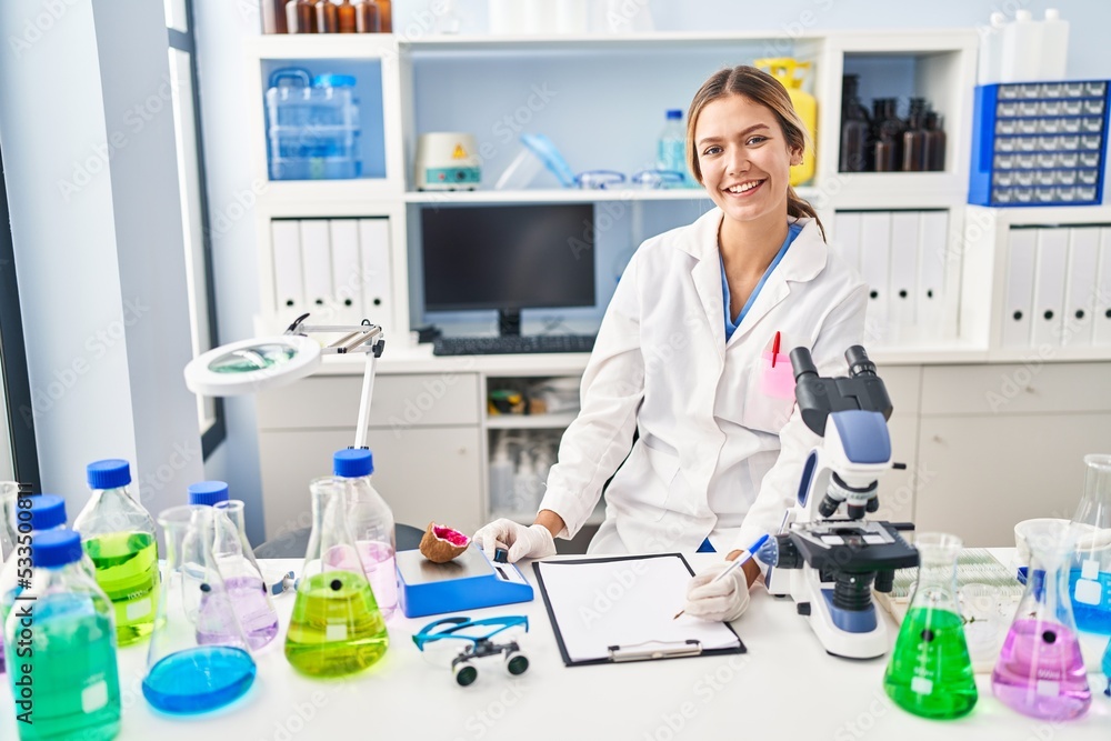Young hispanic woman scientist weighing gemstone writing report at laboratory Young hispanic woman scientist weighing gemstone writing report at laboratory