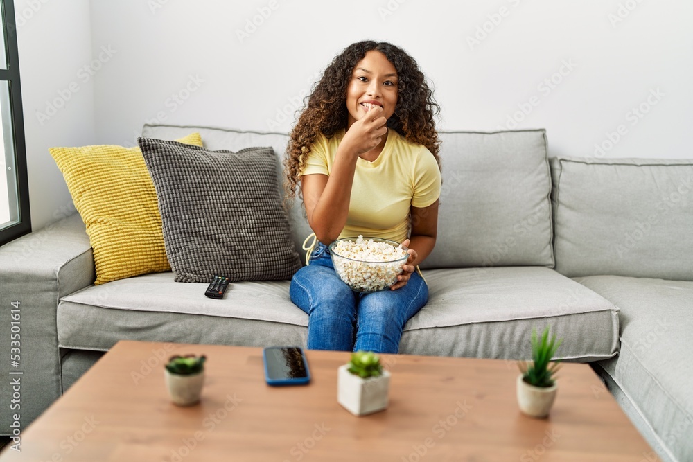 Obraz premium Young latin woman smiling confident eating popcorn at home