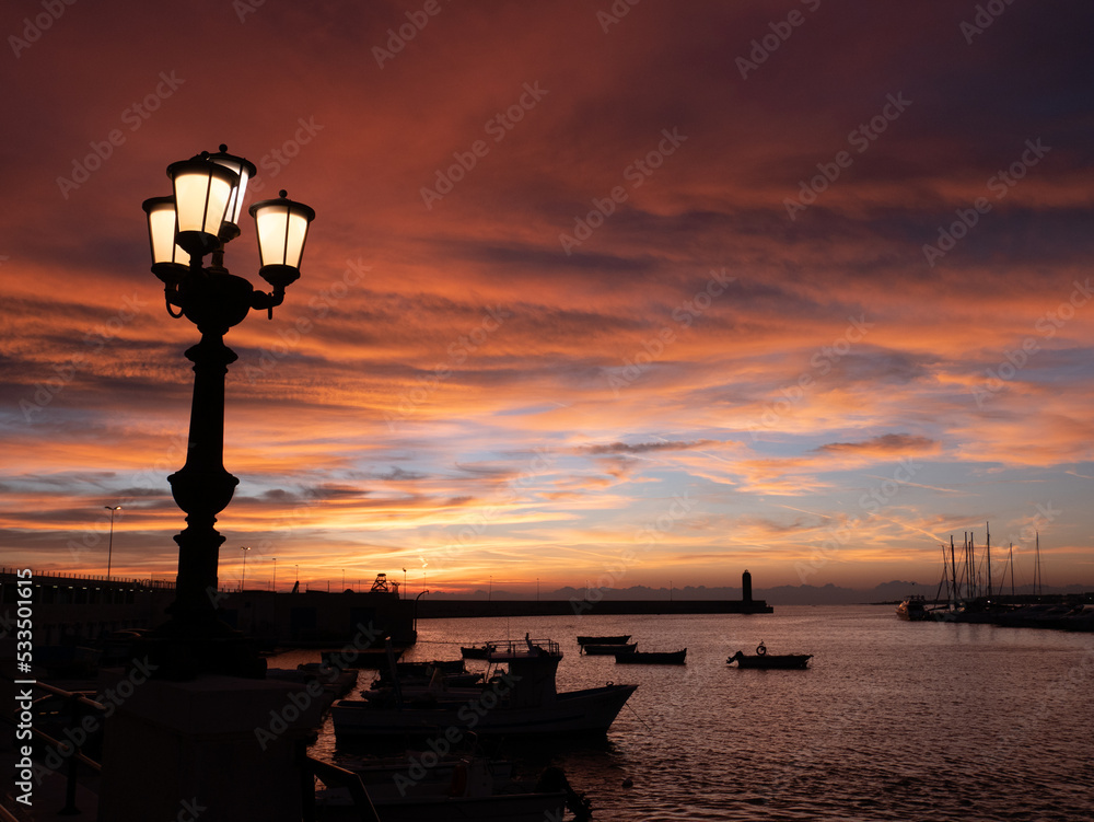 Bari, Alba Lampione acceso Molo di Sant Antonio, lampioni, lungomare, nave, profilo della città, barche sorgere del sole, nuvole