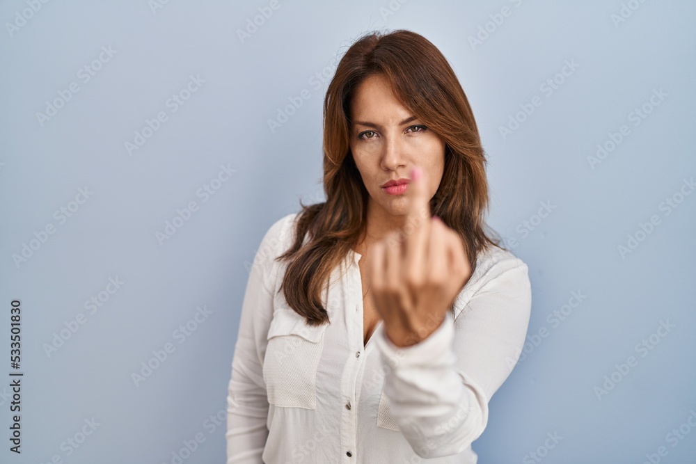 Hispanic woman standing over isolated background showing middle finger, impolite and rude fuck off expression Hispanic woman standing over isolated background showing middle finger, impolite and rude fuck off expression
