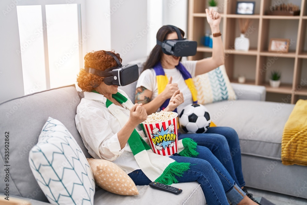 Two women mother and daughter watching soccer match using vr glasses at home Two women mother and daughter watching soccer match using vr glasses at home