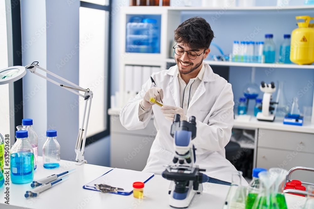 Young hispanic man scientist smiling confident writing on test tube at laboratory Young hispanic man scientist smiling confident writing on test tube at laboratory