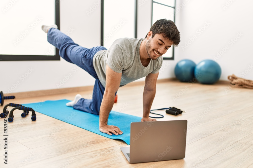 Young hispanic sporty man smiling happy having online sport class at gym center.