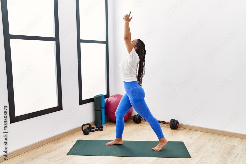 Young african american woman training yoga at sport center