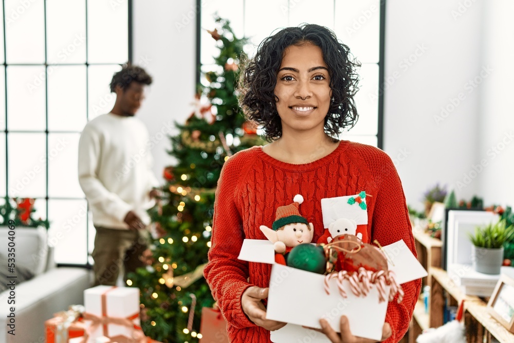 Young hispanic woman standing by christmas tree with decoration with a happy and cool smile on face. lucky person. Young hispanic woman standing by christmas tree with decoration with a happy and cool smile on face. lucky person.