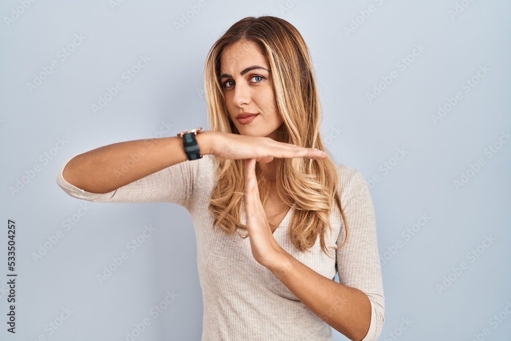 Young blonde woman standing over isolated background doing time out gesture with hands, frustrated and serious face Young blonde woman standing over isolated background doing time out gesture with hands, frustrated and serious face