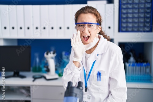 Young caucasian woman working at scientist laboratory clueless and confused with open arms  no idea and doubtful face.