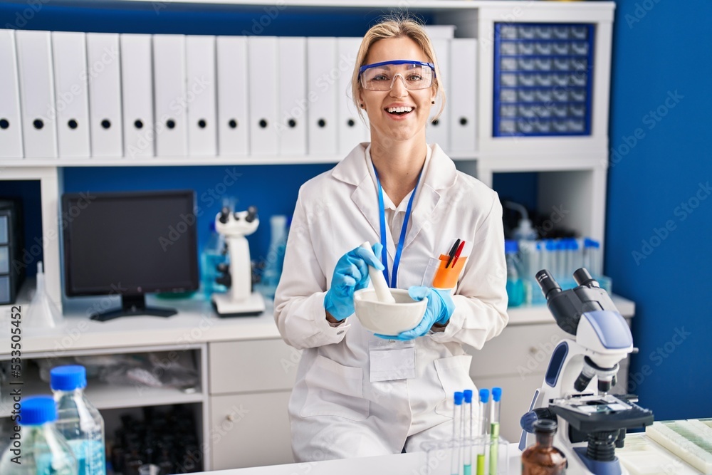 Young caucasian woman working at scientist laboratory smiling and laughing hard out loud because funny crazy joke.