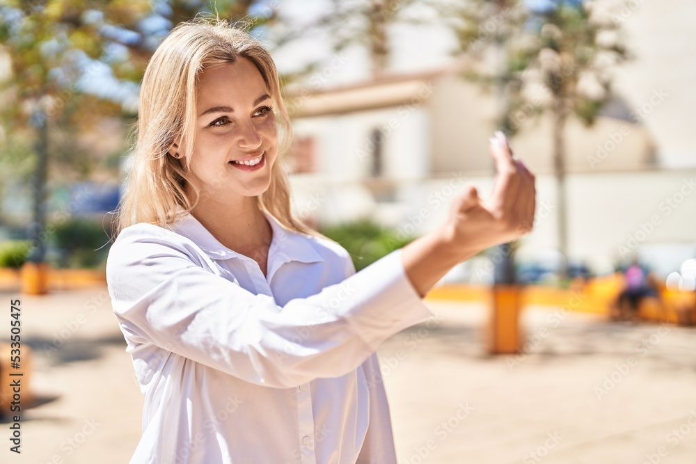 Young blonde woman smiling confident doing coming gesture with finger at park Young blonde woman smiling confident doing coming gesture with finger at park