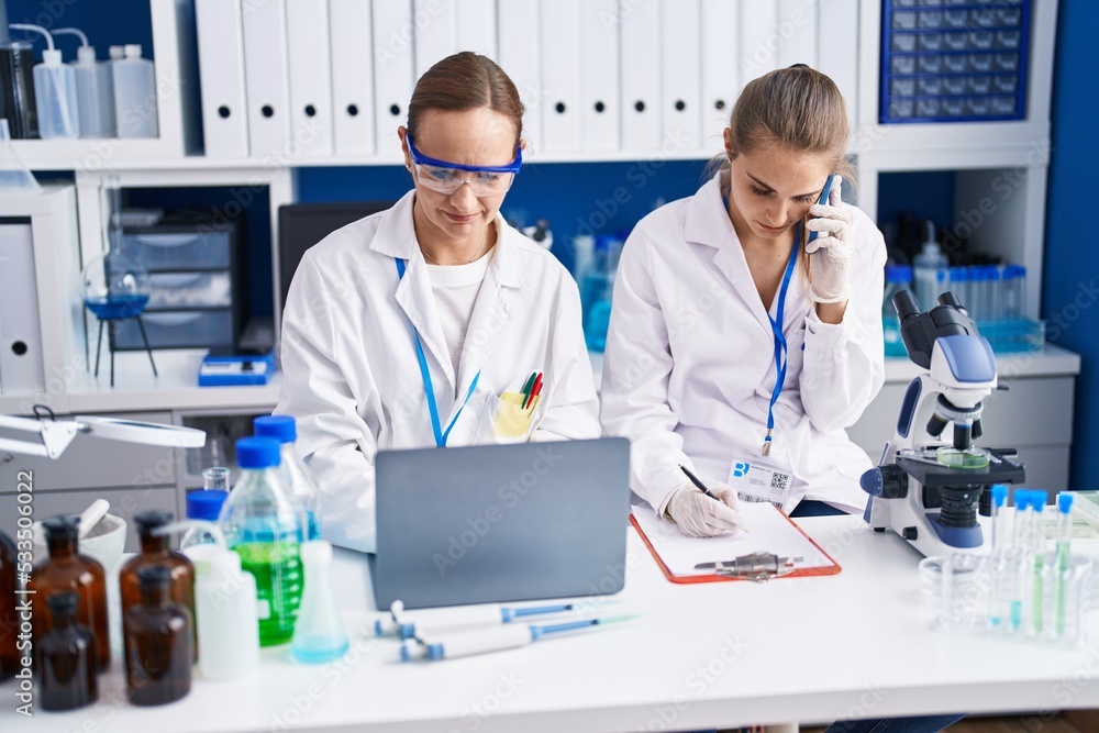 Two women scientists talking on the smartphone working at laboratory Two women scientists talking on the smartphone working at laboratory