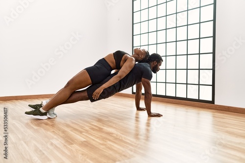 Young african american sporty couple doing push-ups exercise at sport center.