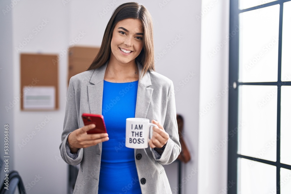 Obraz premium Young beautiful hispanic woman business worker using smartphone drinking coffee at office