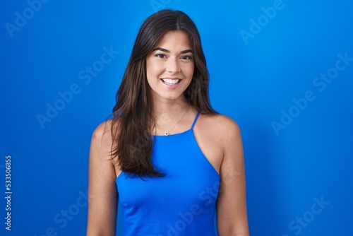 Hispanic woman standing over blue background with a happy and cool smile on face. lucky person. © Krakenimages.com