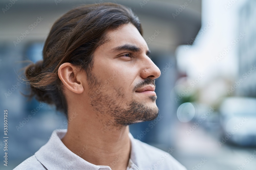 Young hispanic man looking to the side with relaxed expression at street Young hispanic man looking to the side with relaxed expression at street