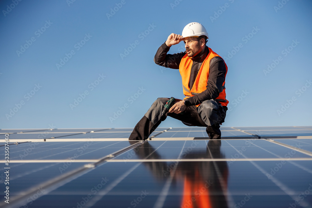 Manual worker is installing solar panels on the rooftop. - obrazy, fototapety, plakaty 